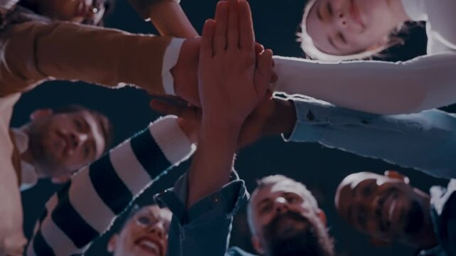 Business professionals stacking hands in support of collaboration, inclusion, and equality in the office. The workplace community huddles together for solidarity, cooperation, and team building.