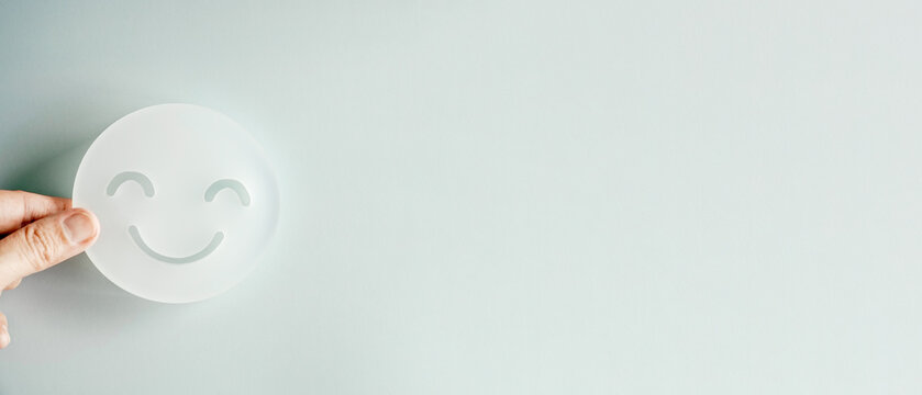 hand holding smile face cutout, happy hormones, brain chemicals, positive mental health concept