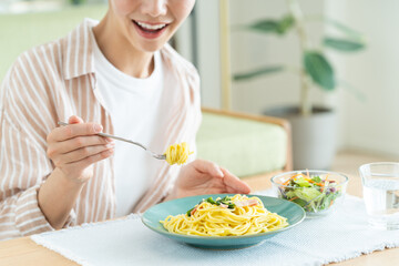 リビングでパスタを食べる若い女性
