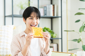 リビングでトーストを食べる若い女性