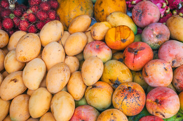 assortment of mangoes and fresh Asian exotic tropical fruits on the counter at the Asian street market in Thailand