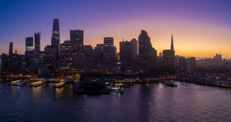 Fototapeta premium San Francisco's skyline is silhouetted against a vibrant sunset sky in the United States. The city's iconic buildings stand tall, creating a dramatic and captivating urban landscape.