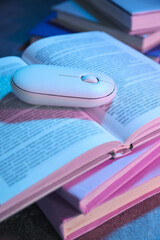 Books with a computer mouse, on a dark background.