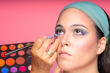 Makeup artist applying eyeshadow to young woman's face