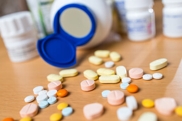 Various colorful medicine tablets on wooden table.