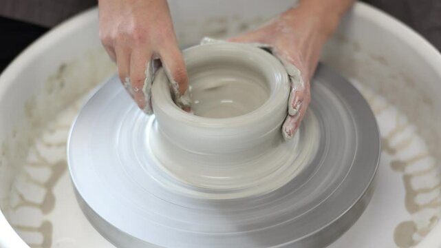 Female potter works with potter weel, craftsman hands close up. Hands of potter making clay pot. High quality 4k footage