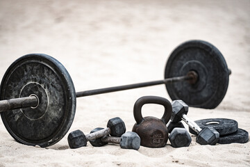 Sport kettlebell training. Sport dumbbells on sand. Sporty outdoor fitness. Sport weightlifting workout. Barbell lifting. Sport motivation exercise.
