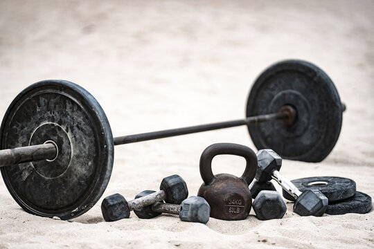 Sport kettlebell training. Sport dumbbells on sand. Sporty outdoor fitness. Sport weightlifting workout. Barbell lifting. Sport motivation exercise.