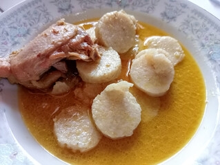 Lontong with chicken opor sauce on a plate with chicken breast on top