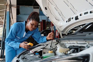 EV car check, Black female mechanic worker inspects and maintains service of electric engine and...