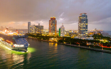 Naklejka premium Cityscape of downtown Miami with sunset glow. Tropical paradise in South Beach. Midnight city lights in Miami. Waterfront view of Miami skyline. Aerial shot of Miami at sunrise. Neon Art Deco. Ocean