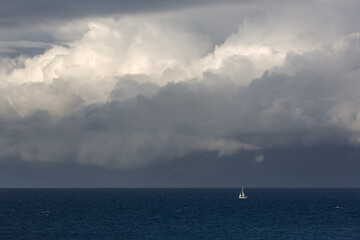 Yacht under sail in rough seas and storm clouds