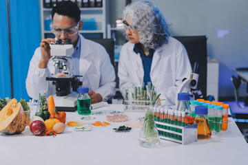 Team Asian scientists in a lab conducting food research using a microscope and lab equipment,...