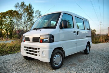 Compact White Mini Van Parked on a Gravel Road in Nature