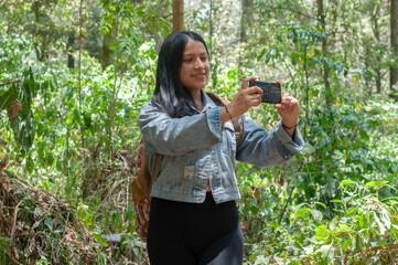 A Woman Enveloped by Nature While Joyfully Taking Photos in a Lush Green Forest Area