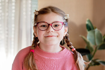 Portrait of a cute little girl with eyeglasses. Happy smiling school child with eye glasses looking at the camera. Childhood concept.