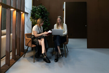 Fototapeta premium Two women engaged in a collaborative work session in a modern office space during the afternoon