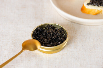 Natural black caviar in the gold jar with toasts on a table. Sturgeon caviar.