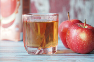 Fresh apple juice served in a glass with ripe apples nearby