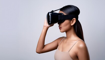 Naklejka premium Young woman wearing a VR headset, seen in profile against a neutral background, engaging with immersive virtual reality technology.