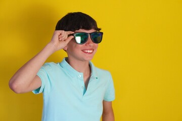 travel and vacation. smiling preteen boy with sunglasses on yellow background.
