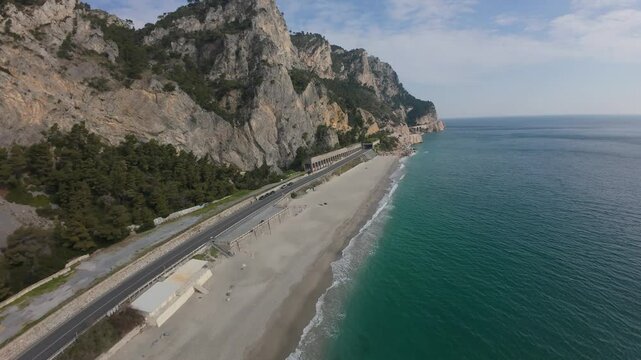 FPV dive then skimming the turquoise waters of Spiaggia del Malpasso, coastal beach, and highway