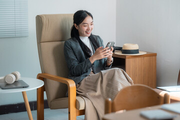 Young businesswoman using mobile phone while relaxing on armchair at home