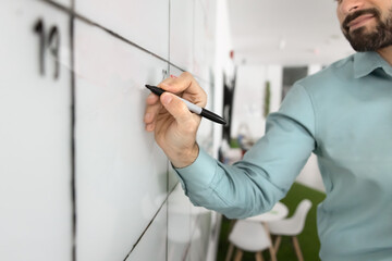 Business project executive leader man writing notes on whiteboard, filling table cells, making work...