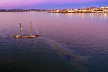 Sunken sailboat in the water, leaking oil into the harbor. Environmental pollution from a shipwreck...