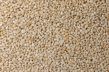A close-up view of white gravel stones creating a textured and natural background. The small pebbles form an abstract pattern, commonly used for landscaping, construction, and decorative purposes