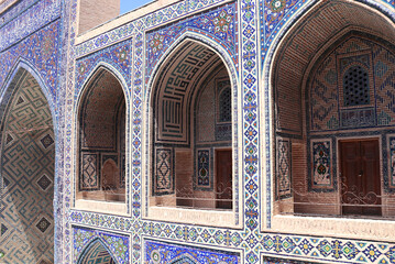 Famous landmark - Ulugh Beg Madrasah on Registan square, Samarkand, Uzbekistan. Arches with tile ornament in the courtyard of Ulugh Beg Madrasa. Text on the wall is a quote from the Quran