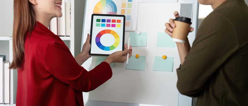Creativity and Collaboration. A designer presenting color palettes on a tablet during a brainstorming session.
