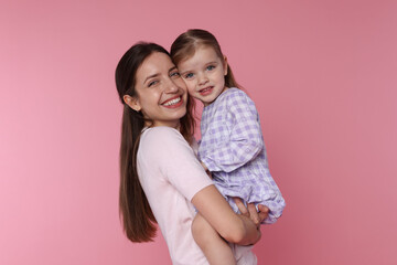 Portrait of happy mother with her cute little daughter on pink background