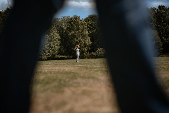 A girl stays on the football field. view through the leg other person.