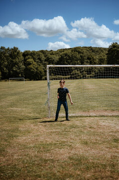 A boy stands in front of a football goal. Goalkeeper