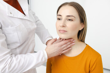 Doctor palpates of woman's neck for diagnostics of thyroid diseases and hypothyroidism at medical clinic. Thyroid treatment