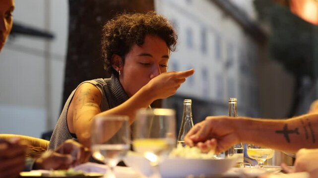 Young woman tasting food at outdoor restaurant table