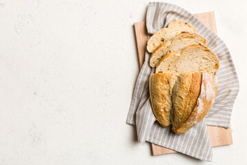 Freshly baked bread slices on cutting board against white wooden background. top view Sliced bread