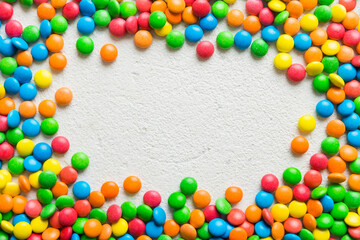 Obraz premium Mixed collection of colorful candy, on colored background. Flat lay, top view. frame of colorful chocolate coated candy