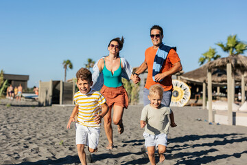 Happy family running on the beach during summer vacation