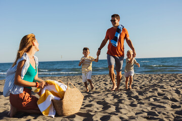 Happy family running on sandy beach during summer vacation