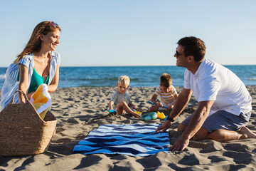 Obraz premium Family enjoying summer vacations on the beach laying down a towel