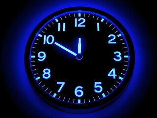 Illuminated Blue Clock Face on Black Background, Time Measurement, Midnight, Ten O'clock