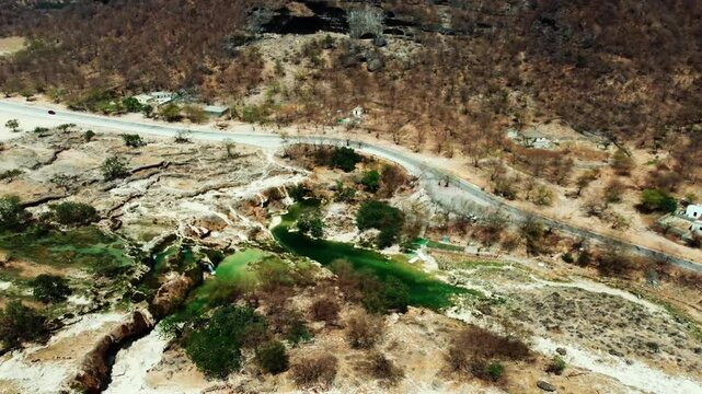 Aerial view of Wadi Darbat, a lush oasis near Salalah, Oman! See its waterfalls and scenic beauty. Watch now!