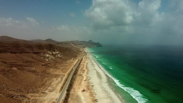 Breathtaking aerial view of Mughsail Beach, Oman! White sands meet turquoise waters and dramatic cliffs. Watch now!
