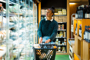 Customer choosing products in organic supermarket refrigerator section