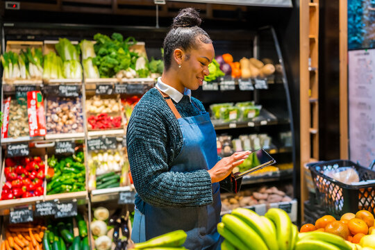 Saleswoman using digital tablet and managing inventory in organic supermarket
