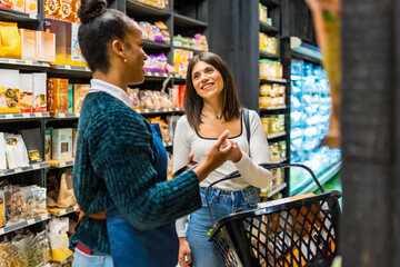 Saleswoman advising customer choosing products in organic supermarket