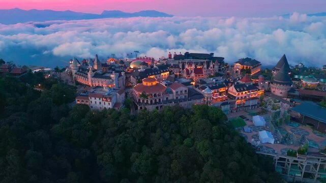 Aerial view is lunar castles of Bana Hills at pink sunset time with clouds down. The famous tourist destination of Da Nang, Vietnam. Near Golden bridge.