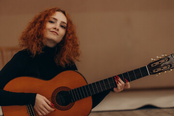 Fototapeta premium Young Woman with Red Hair Playing Acoustic Guitar Indoors